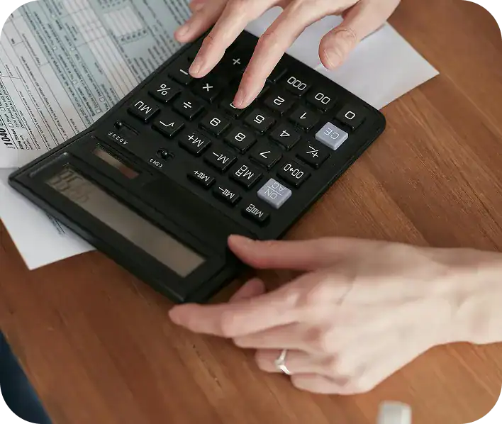 Person using a calculator on a desk with financial documents.